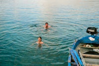 two people swimming in the water next to a boat