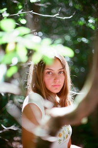 a girl is sitting in a tree in the woods