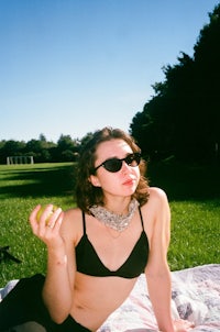 a woman in a black bikini sitting on a blanket