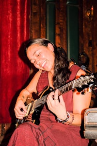 a woman in a red dress playing a guitar